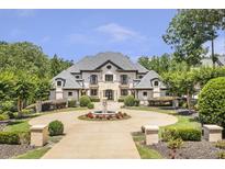Stately two-story home featuring a circular driveway, a fountain, a manicured lawn, and lush landscaping at 4317 Oglethorpe Nw Loop, Acworth, GA 30101