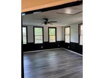 Bright living room with updated gray wood flooring, a modern ceiling fan, and multiple windows at 1120 Brandon Hill Way, Jonesboro, GA 30238