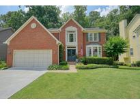 Charming two-story brick home featuring a well-manicured lawn and an attached two-car garage at 4138 Glenlake Nw Ter, Kennesaw, GA 30144