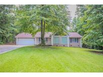 Charming single-story home with a well-manicured lawn and attached garage, set amidst lush greenery at 45 Kelsey Way, Palmetto, GA 30268