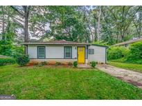 Charming one-story home features a classic design, manicured lawn, and inviting yellow front door at 1024 Regis Rd, Atlanta, GA 30315