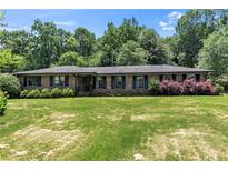 Charming brick home featuring lush lawn, mature trees, and meticulously maintained landscaping at 2532 Millbrook Dr, Snellville, GA 30078