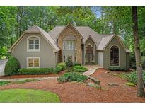 Stunning stone and stucco home with meticulously landscaped front yard in a serene wooded setting at 4435 Pemberton Cv, Johns Creek, GA 30022