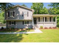 Charming two-story home with gray siding, black shutters, a covered front porch, and landscaped yard at 2880 Brett Nw Cir, Acworth, GA 30101