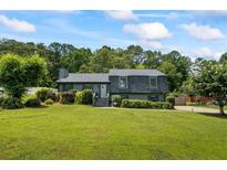 Charming home showcasing a lush, green front yard and mature trees, creating a welcoming curb appeal at 110 Village Ct, Woodstock, GA 30188