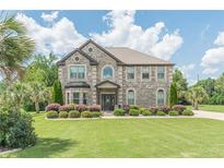 Beautiful two-story brick home featuring a manicured lawn, mature landscaping, and a welcoming entrance at 1405 Rainey Way, Hampton, GA 30228
