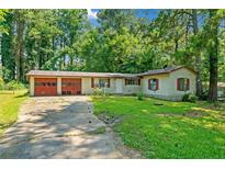 Ranch style home with attached two-car garage and mature trees surrounding at 4235 Apache Se Dr, Acworth, GA 30102