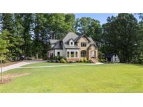 Charming two-story home with a brick facade, complemented by a well-manicured lawn and mature trees at 6685 Driskell Rd, Cumming, GA 30041