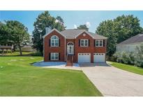 Inviting brick home featuring a two-car garage, manicured lawn, and a charming front entrance with decorative windows at 503 Rising Dr, Woodstock, GA 30189