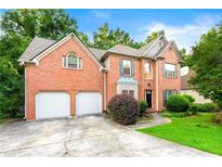 Charming two-story brick home with a two car garage and well-manicured landscaping at 2004 Township Dr, Woodstock, GA 30189