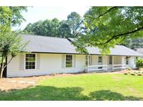 Charming single-story home featuring white siding, a covered porch, and a well-maintained lawn at 5974 Sw Four Winds Sw Dr, Lilburn, GA 30047