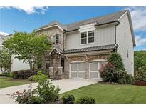 Charming two-story home featuring a blend of brick and siding, complemented by a well-manicured lawn and an attached two-car garage at 935 Grove Valley Drive Dr, Cumming, GA 30041