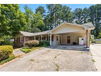 Charming single-story home featuring a large, cracked concrete driveway and carport at 824 Hickory Ridge Sw Rd, Lilburn, GA 30047