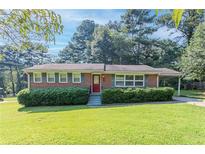 Charming brick home with a manicured front lawn and a red front door at 573 Allgood Rd, Stone Mountain, GA 30083
