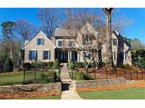 Charming brick two-story home with mature trees, a black metal fence, and manicured front yard at 1600 Nottingham Ne Way, Atlanta, GA 30309