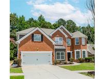 Traditional two-story red brick home with a manicured lawn, attached two car garage and a circular driveway at 2023 Jameson Cir, Lawrenceville, GA 30043