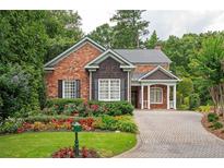 Charming brick home featuring lush landscaping, a well-manicured lawn, and a brick driveway at 1006 Arbor Ne Trce, Atlanta, GA 30319
