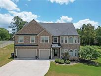 Charming two-story brick home boasts a three-car garage and well-manicured lawn at 293 Ironwood Dr, Stockbridge, GA 30281