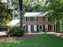 Charming two-story brick home with black shutters and a lush green lawn surrounded by mature trees at 21 Queen Anne Se Dr, Mableton, GA 30126