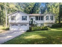 Split level home features a 2-car garage, classic white siding, green shutters, and a cozy front porch at 1180 Springs Dr, Canton, GA 30115