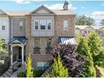 Charming brick townhome featuring a covered entrance, upper level balcony and manicured landscaping at 2520 Carmel Way, Alpharetta, GA 30009