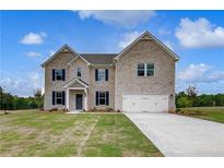 Beautiful two-story brick home with a two-car garage and manicured lawn on a sunny day at 145 Compass Rd, Hampton, GA 30228