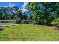 A charming single-story home with a lush green lawn and mature trees providing ample shade at 3904 W Hilda Cir, Decatur, GA 30035