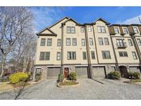 Townhome exterior featuring multiple stories, individual garages, manicured landscaping, and a brick driveway at 255 Southerland Ne Ter # 207, Atlanta, GA 30307