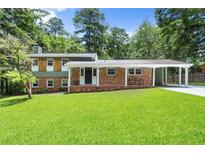 Charming brick home with a lush front lawn and attached carport, providing convenient parking at 6875 Sunny Brook Lane Northeast, Sandy Springs, GA 30328
