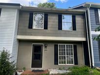 Two-story townhouse featuring a covered front porch, neutral color, black shutters and brick entry at 8564 Jamestown Way, Jonesboro, GA 30238