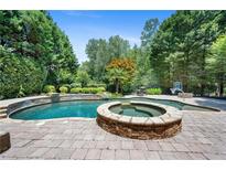 Stunning backyard pool with a connected jacuzzi, stone surround, and lush landscaping for outdoor entertainment at 307 Heritage Overlook, Woodstock, GA 30188