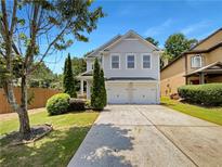 Two story home with a two car garage, driveway, and manicured landscaping at 2470 Arnold Mill Rd, Lawrenceville, GA 30044