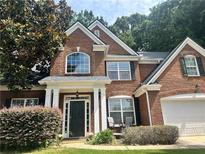 Charming red brick two-story home featuring a well-manicured front yard and inviting front porch at 1038 Island View Ct, Buford, GA 30518