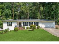 Charming single-story home with a well-manicured lawn, mature trees, and an attached garage at 5360 Fieldgreen Dr, Stone Mountain, GA 30088
