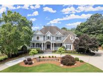 Beautiful two-story home featuring manicured front lawn and driveway with lush, mature landscaping and a welcoming front porch at 6325 Haddington Ln, Suwanee, GA 30024