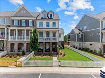 Charming townhome showcasing a manicured front yard, white picket fence and lovely brick and siding elevation at 630 Brashy St, Woodstock, GA 30188