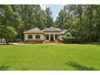 Beautiful single-story home boasts lush lawn, mature trees, and inviting curb appeal at 105 Postwood Dr, Fayetteville, GA 30215