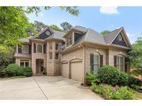 Charming two-story brick home with a well-manicured lawn, a three car garage and an arched entryway at 5355 Highland Pine Ln, Mableton, GA 30126