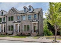 Charming brick townhome featuring a welcoming front porch and manicured landscaping at 130 W Main Street # 1, Buford, GA 30518