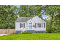 Charming brick home featuring a well-manicured lawn, blue shutters, and a cozy front porch, nestled among mature trees at 512 Allendale Dr, Decatur, GA 30032