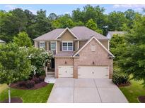 Charming two-story home boasts a brick and tan exterior, lush landscaping, and a two-car garage at 5473 Heatherbrooke Nw Dr, Acworth, GA 30101