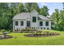 Charming home featuring professionally landscaped lawn with rock terracing, lush shrubs, and black frame windows at 6070 Lively Ct, Cumming, GA 30040