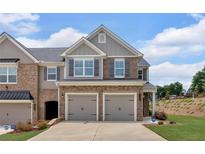 Two-story townhome showcasing a two-car garage and brick and siding exterior under a cloudy sky at 1311 Park Center Cir, Austell, GA 30168