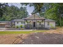 Charming home with a welcoming front porch, black and white trim, and lush landscaping at 5601 Due West Rd, Powder Springs, GA 30127