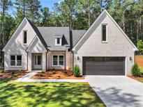 Charming, newly built home with light brick, manicured lawn, and a paved driveway at 2335 Azalea Dr, Loganville, GA 30052