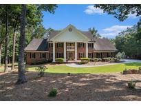 Classic red brick home featuring white columns, a manicured lawn, and mature trees at 402 Clyde Ct, Mcdonough, GA 30252