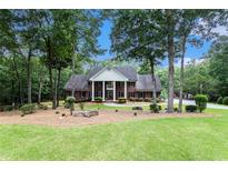 Charming brick home with a manicured lawn, mature trees, and a circular driveway at 402 Clyde Ct, Mcdonough, GA 30252