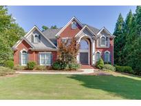 Beautiful two-story brick home with mature trees, manicured lawn, and classic architectural details at 1777 Water Springs Way, Dacula, GA 30019
