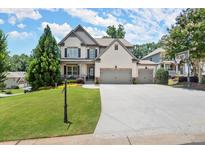 Charming two-story home with a well-manicured lawn, a driveway, and a basketball hoop near the garage at 5605 Miners Rdg, Cumming, GA 30028