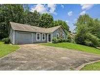 Charming single-story home featuring a stone accent wall, attached garage, and well-maintained front lawn at 1050 Chapman Circle Cir, Stone Mountain, GA 30088